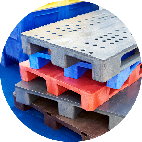 Stack of colorful plastic pallets in gray, red, and blue for storage in a warehouse setting.